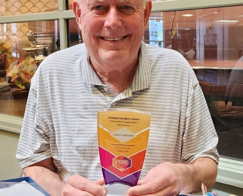 A man holds an award and smiles