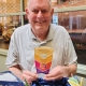 A man holds an award and smiles